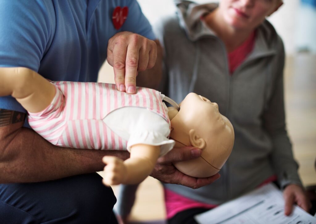 Emergency paediatric first aid - delivering CPR on a baby dummy